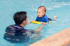 Baby swimming with adult